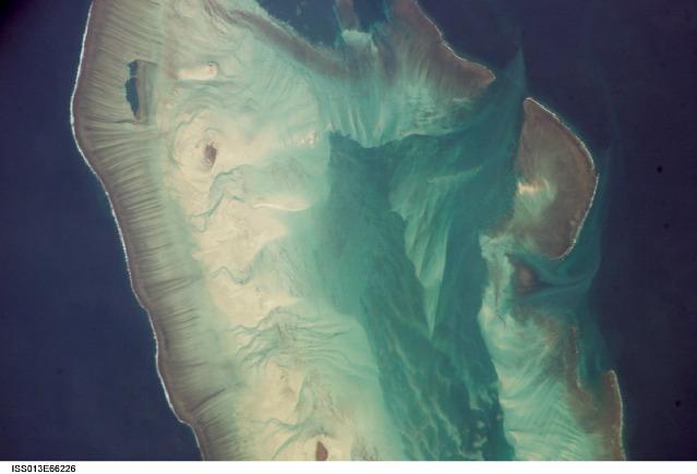 Close-up of Ashmore Island showing some of its lighter-hued peripheral current and sediment channels, and darker-colored central lagoon. Image courtesy of NASA.
