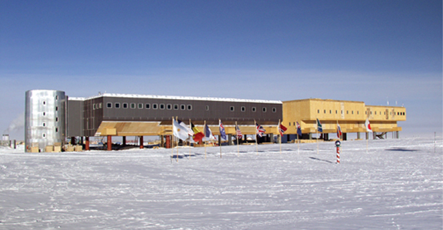 A view of the Amundsen-Scott South Pole Station. Even though built on stilts to prevent snow accumulation, some annual snow buildup does occur (about 20 cm (8 in) per year). The  station can be elevated to prevent its becoming buried in the snow. In the foreground is the ceremonial South Pole and the flags for the original 12 signatory nations to the Antarctic Treaty. Image courtesy of the National Science Foundation.