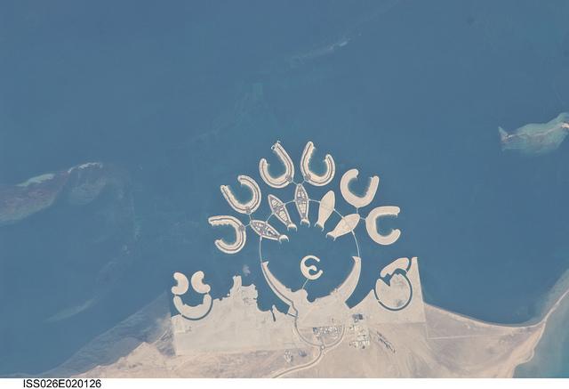 The Durrat Al Bahrain complex is featured in this image photographed from the International Space Station. Set at the southern end of Bahrain Island, at the furthest point from the cities of the kingdom, is this complex of 15 artificial islands designed for residential living and tourism with luxury hotels and shopping malls. Aimed at a cosmopolitan clientele, the Durrat Al Bahrain includes 21 sq km (8 sq mi) of new land for more than 1,000 residences that has been designed as The Islands (six crescent-shaped "atolls" leading off five fish-shaped "petals"). The Crescent at the bottom of the ring is the heart of the complex and features shops, restaurants, hotels, apartments, offices, and schools. The Central  Island is dedicated to one, ultra-luxurious hotel. The three, thick, crescent-shaped islands at the lower left make up the Durrat Marina; the area between the Marina and the Crescent is a golf course. Image courtesy of NASA.