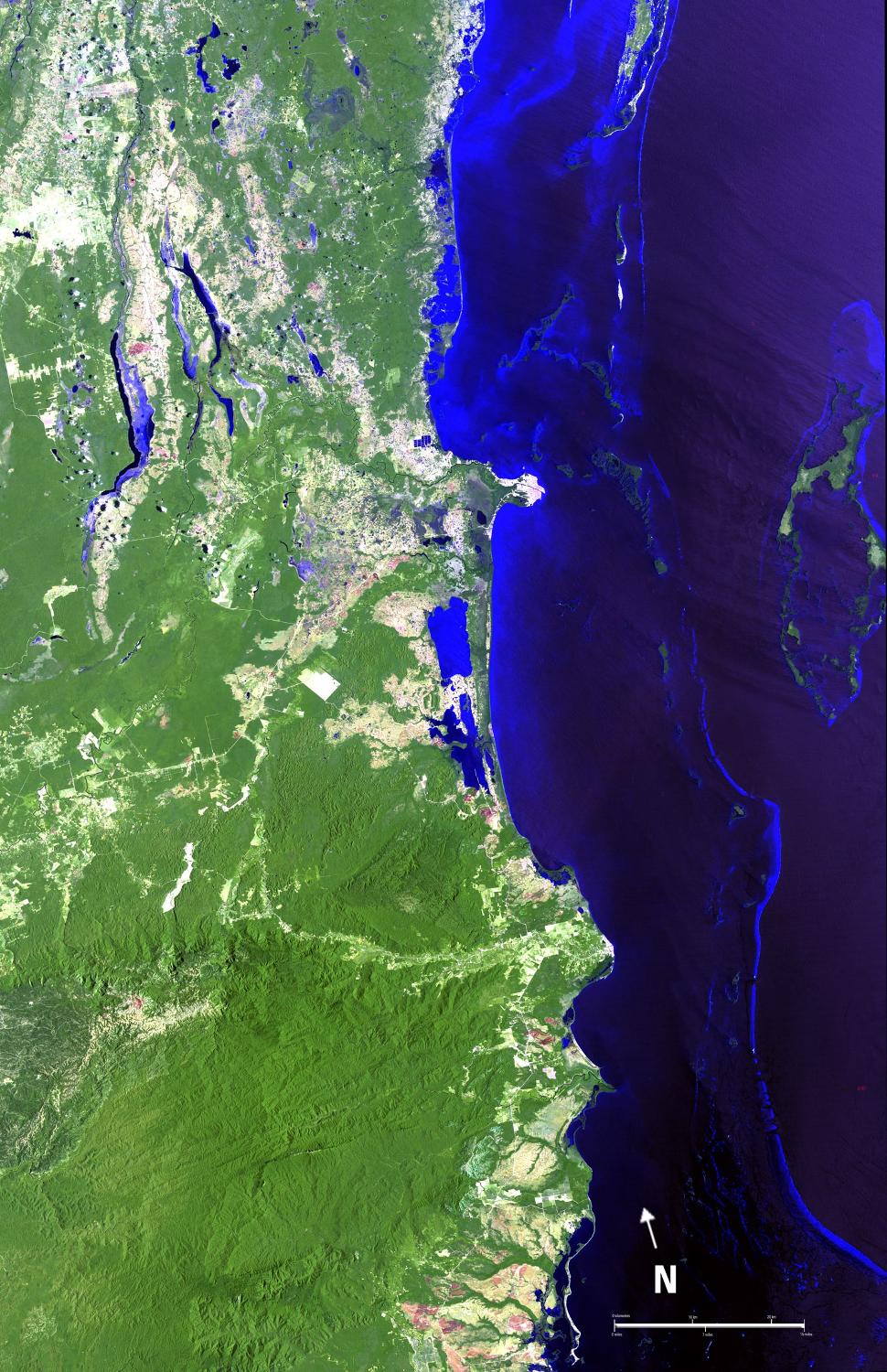 A view of the Belize Barrier Reef, the longest coral reef in the Western and Northern Hemispheres and second largest worldwide (after the Great Barrier Reef of Australia). Running the entire coastline of Belize in Central America, the Belize Barrier Reef supports a large number of patch reefs, shoals, and over 1,000 islands called "cayes." Most of these cayes, and the entire coastline of the country outside of settlements, are protected by huge forests of mangrove. The Turneffe Atoll is shown on the right side of the image. As one of three large coral atolls outside of the reef, it stretches over 48 km (30 mi) long and 16 km (10 mi) wide and is surrounded by one of the most fertile marine ecosystems in the world - a natural nursery for fish, sharks, and crocodiles. Belize City is situated on the outlet of land near the center of the image. It is the largest city in Belize and is the nation's principal port and its financial and industrial hub. Image courtesy of NASA.