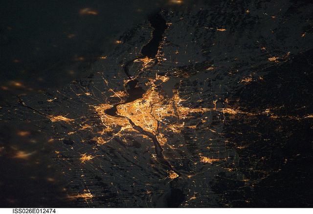 A night view of the Montreal metropolitan area is featured in this image from the International Space Station. This photo of the Montreal, Quebec  metropolitan area (center) illustrates the extent of urbanization made clearly visible by city lights at night. Major roadways and industrial areas are traced by bright white lighting, while the adjacent residential and commercial land uses are characterized by more diffuse yellow-gold lighting. Rivers and other water bodies appear black, while the surrounding rural countryside is faintly illuminated by moonlight. Blurry areas at top and bottom left are caused by cloud cover. Montreal is the largest city in the dominantly French-speaking province of Quebec, and the second-largest in Canada, after Toronto. While the city of Montreal proper is located on - and almost completely covers - the Island of Montreal at the confluence of the St. Lawrence (center) and Ottawa Rivers (not visible), the city takes its name from Mont Royal located at the city's center. Image courtesy of NASA.


