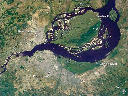 The Luizi Structure, located in southeastern Congo, is a crater covered by grasses up to a meter (3 ft) high. The crater seen in this satellite image has about a 17 km (11 mi) diameter, with an intermittent ring about 5.2 km (3.2 mi) across, and a smaller, center ring about 2 km (1.2 mi) across. Around the perimeter of the crater, a rim rises approximately 300 to 350 m (980 to 1,150 ft) above the interior. In short, Luizi is a well-preserved, moderately sized, complex crater. Exactly when Luizi formed is difficult to answer. Researchers estimate that nearby rocks are 575 million years old - more than 300 million years older than the first dinosaurs. But besides knowing that the impact cannot be older than the rock layers it disrupted, geologists still cannot say when the impact occurred. Photo courtesy of NASA.