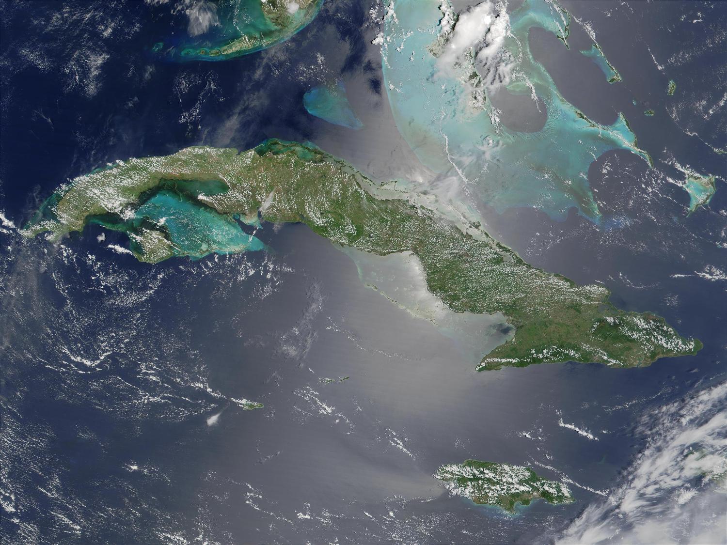 Satellite image of Cuba (center) and Jamaica (lower right). The southern tip of Florida, the Florida Keys, and the Florida Strait appear at the top. The bright blue green color around the islands, particularly around those of the Bahamas in the upper right, is likely due to the brighter solar reflection over the more shallow waters that surround the islands. Image courtesy of NASA. 