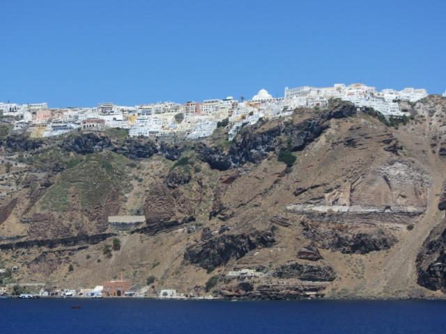 Houses perched on top of 300 m (980 ft) cliffs in the city of Fira on Santorini (Thera) Island in the Mediterranean Sea. The cliffs show the many layers of past volcanic eruptions.  In ancient times, the island was called "Thera." In the 14th century it was named "Santorini" - in honor of Saint Irene - by the feudal crusader Latin Empire. It was renamed "Thera" in the 19th century but is still commonly called "Santorini." Fira is the principal city on the island.  Santorini Island is the southernmost of the Greek Cyclades.
