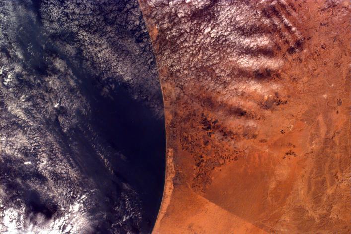 This image covers an area roughly 100x150 km; due to shuttle orientation, north is located at approximately eleven o'clock in this image. Shown are the Gaza Strip (roughly the center third of the coastal strip) and the Mediterranean Sea. The straight-line Egypt-Israel border is apparent in the lower center because of a difference in vegetation patterns, the Egyptian side (south) being less vegetated perhaps due to heavy use of the land for grazing. Photo courtesy of NASA.
