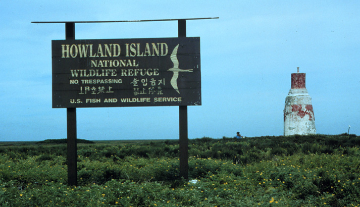 Sign on Howland Island proclaiming its status as a wildlife refuge. The "Earhart Light" day beacon (an unlighted nautical sea mark) is on the right. Photo courtesy USFWS/C. Newton