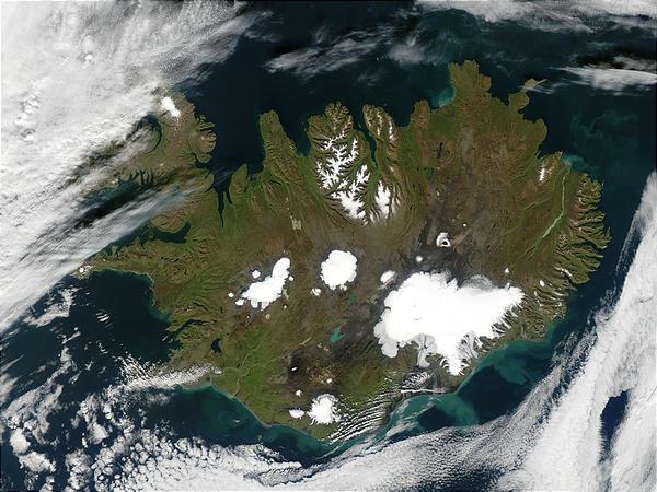 Summer is winding to a close on 9 September 2002, but even Iceland is still showing some summer color, its perimeter tinged with green, while its large permanent ice caps stand out brightly against the volcanic rock surrounding them. The largest ice cap, Vatnajokull, actually rests on top of three active volcanoes. The heat from these volcanoes causes the underside of the ice cap to melt, slowly filling the calderas. Eventually the caldera spills over and releases a torrent of water known as a glacial melt flood. This volcanic activity happens because a tectonic boundary runs roughly northeast-southwest through the island country, and the two plates are pulling away from each other, causing magma to well up from deep in the Earth. The brightly colored lakes and coastal waters are the result of very fine, and highly reflective sediment that is ground to bits by the immense weight of the glaciers and washed out with glacial runoff. Image courtesy of NASA.