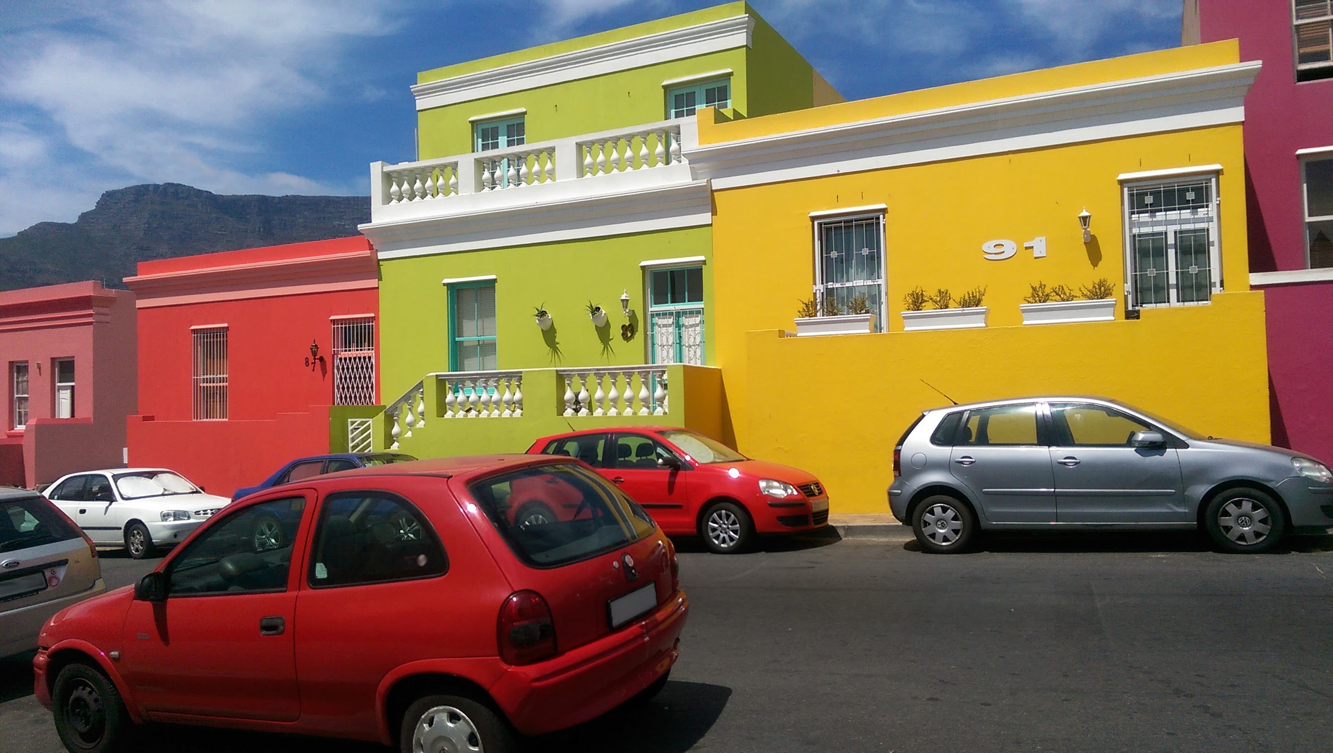 Brightly colored cars complement the brightly painted exteriors of buildings in the Bo-Kaap District of Cape Town. 