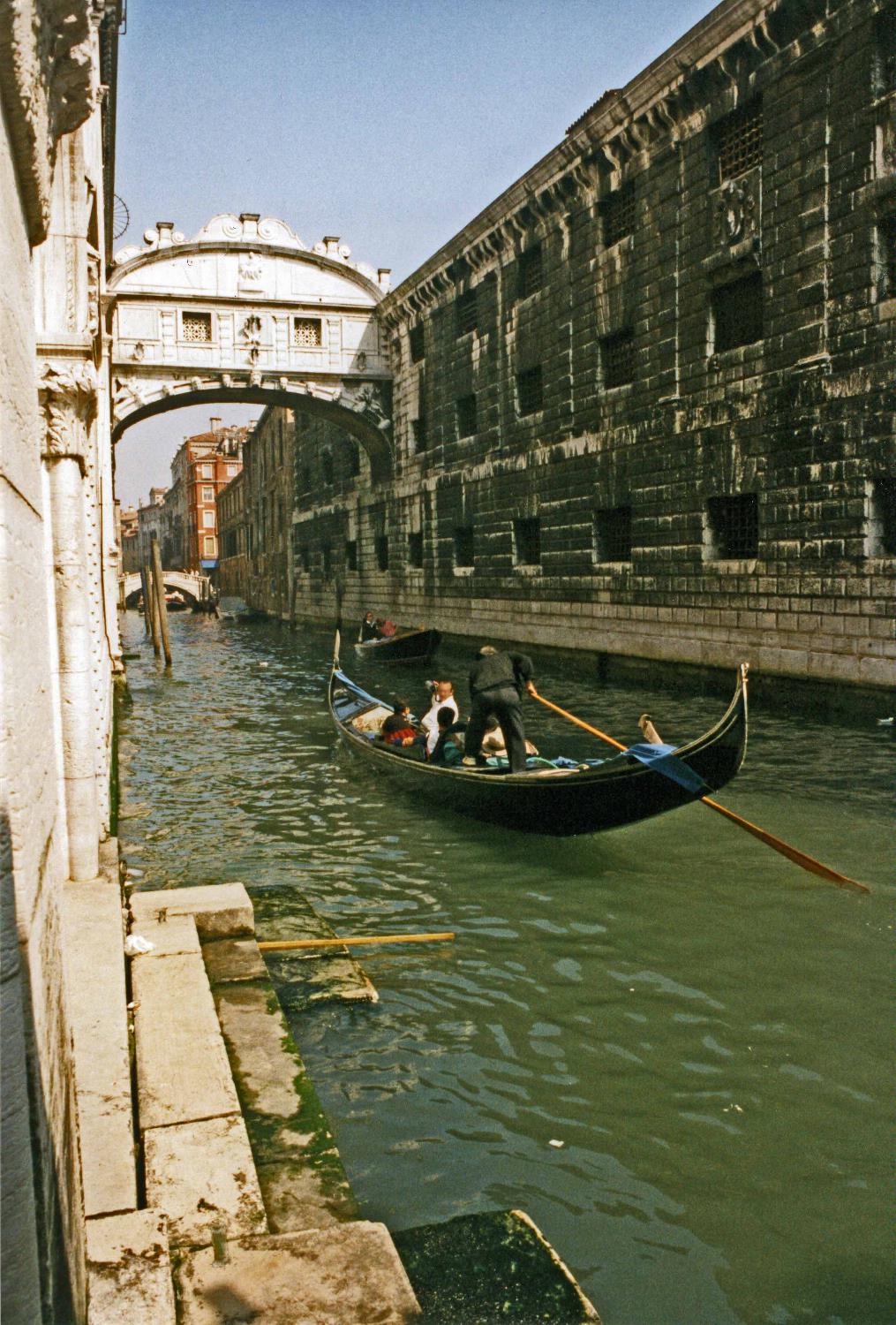Gondola on a Venetian canal approaching the Bridge of Sighs. 