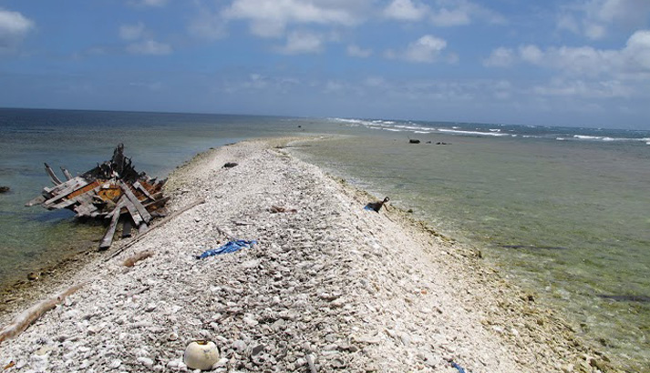 There are only a few small spits of coral and shell rubble that break the surface at Kingman Reef National Wildlife Refuge. This bow of a shipwreck - along with much additional submerged material - was removed in January 2014. Wreck debris buffeted by waves can cause a great deal of damage to coral. Image courtesy of the USFWS.