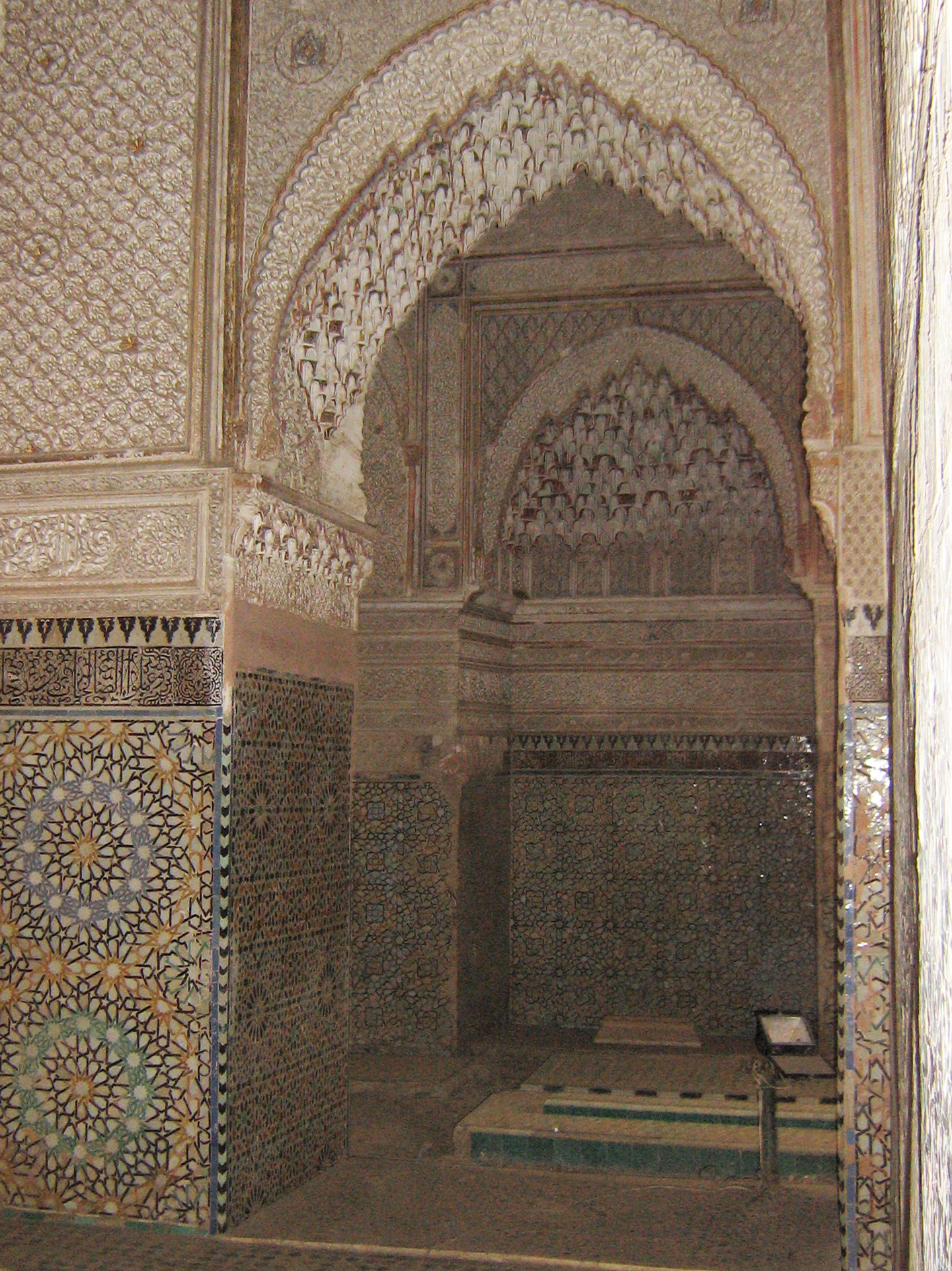 The Saadian Tombs are a historic royal necropolis in Marrakech that date to the time of the Saadian Dynasty (1549-1659). They are located on the south side of the Kasbah Mosque, inside the royal kasbah (citadel) district of the city. Because of the beauty of their decoration, the tombs have become a major attraction for visitors to Marrakech. This view offers a glimpse into the Chamber of the Three Niches from the main mausoleum. 