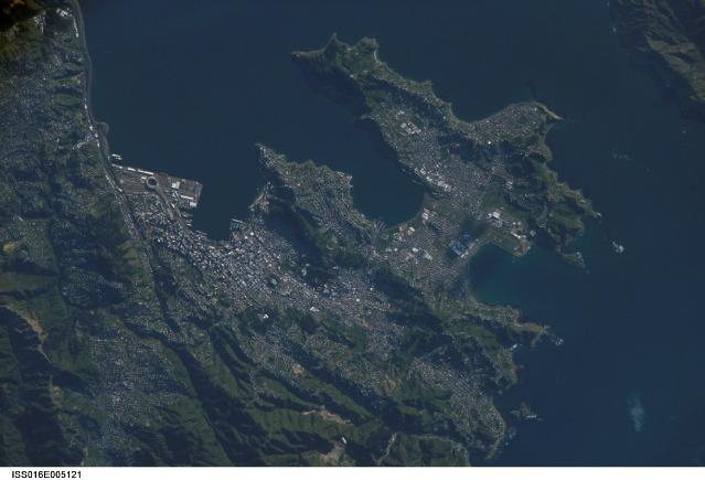 A view of New Zealand's capital of Wellington, located at the southwestern tip of North Island near the Cook Strait. The city is the second largest in New Zealand (after Auckland), and at 41 degrees south latitude, it is the southernmost capital city in the world. Five major geologic faults run through the Wellington municipality. Recognition of the potential seismic hazard in the metropolitan area has led to the adoption of building codes to maximize structural resistance to earthquake damage. Click on photo to increase resolution. Image courtesy of NASA.