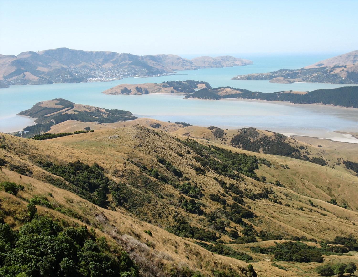 This photo was taken looking southeast on the Banks Peninsula on South Island. The peninsula was formed from eroded remnants of two large composite shield volcanoes, the dominate craters forming the Lyttelton and Akoroa Harbors. The mountainous nature of the peninsula is atypical within the surrounding region.