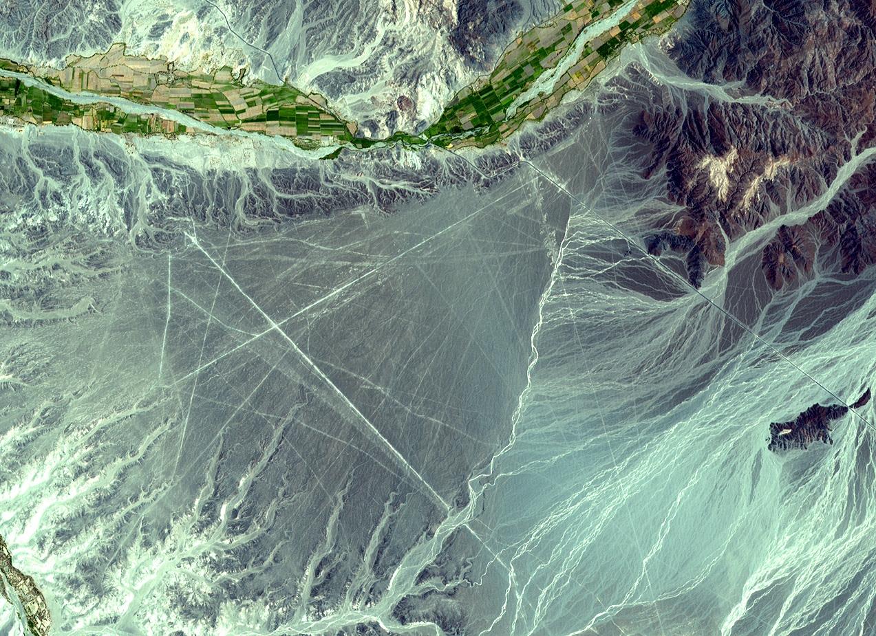 The Nasca Lines, located in the desert coastal plain of Peru 400 km south of Lima, were first observed in the 1920s when commercial airlines began operating in the area. Clearly seen from the air, the Lines were made by removing the iron-oxide coated pebbles which cover the surface of the desert. The lighter shade of the exposed ground contrasts with the color of the gravel. South of the Nasca Lines, archaeologists have now uncovered the lost city of the Line-builders. Known as Cahuachi, it was built nearly 2,000 years ago and was mysteriously abandoned 500 years later.
Image courtesy of NASA.