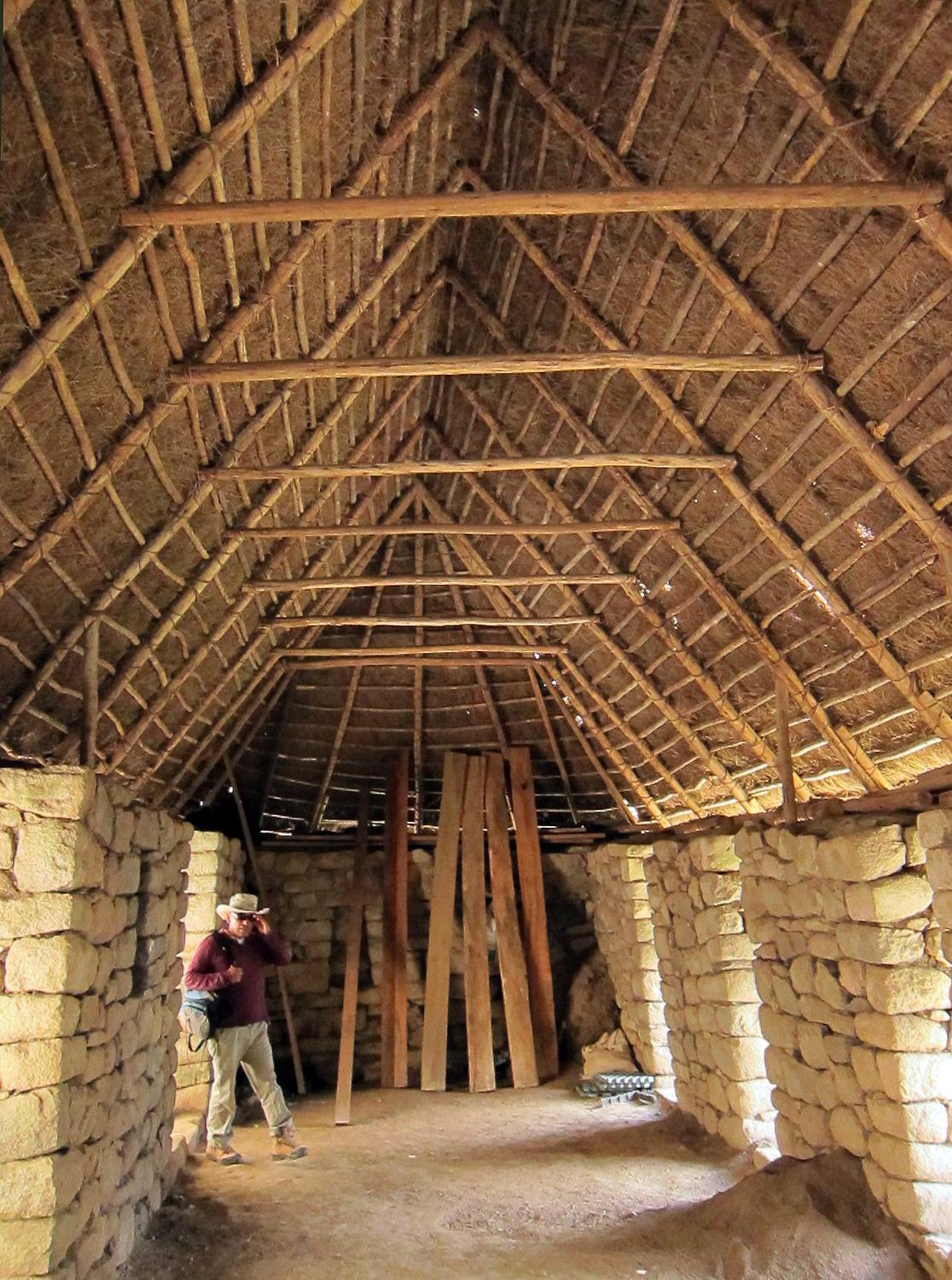 The inside of a large Machu Picchu structure with a thatched roof. 
