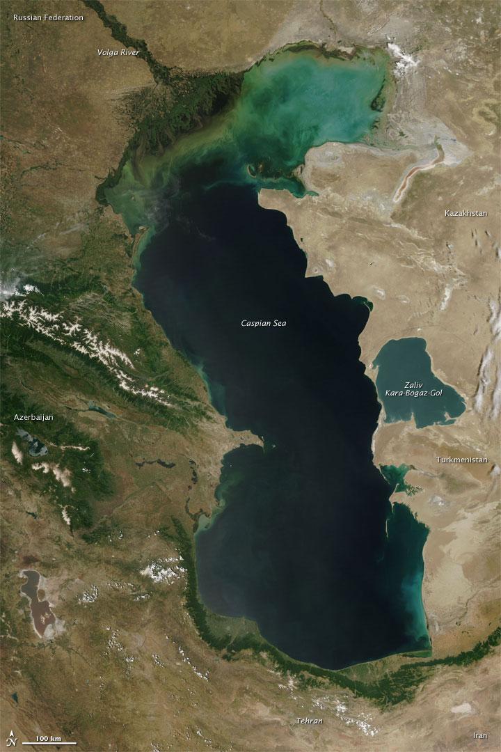 Measured by surface area, the Caspian Sea is the world's largest inland water body. It covers roughly 371,000 sq km (143,200 sq mi) and borders five countries. To the ancient Greeks and Persians, the lake's immense size suggested it was an ocean, hence its name. A large expanse of clear sky permitted this natural-color satellite image of the entire water body. The color of the Caspian Sea darkens from north to south, thanks to changes in depth and perhaps sediment and other runoff. The northern part of the lake is just 5 to 6 m (16 to 20 ft) deep. The southern end, however, plunges more than 1,000 m (3,300 ft). Just as the lake reaches a greater depth in the south, the nearby land reaches a greater height. The mountains of northern Iran line the southern end of the giant lake, and emerald green vegetation clings to those mountain slopes. In marked contrast to the mountains, sand seas line the southeastern and northern perimeters of the lake, and marshes occur along the lake shores in Azerbaijan to the west. Multiple rivers empty into the Caspian Sea, the Volga being the largest. Lacking an outlet, the Caspian Sea loses water only by evaporation, leading to the accumulation of salt. Although a lake, the Caspian is not a freshwater lake; the water delivered by the Volga River minimizes the lake's salt content at the northern end, but the Caspian grows more saline to the south. Kara-Bogaz-Gol is a saline inlet along the lake's eastern perimeter. Image courtesy of NASA. 