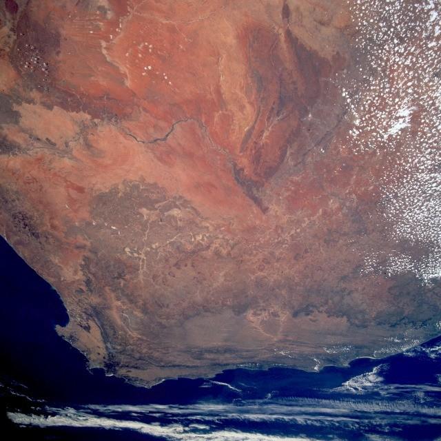 The reddish-brown Kalahari Desert with its northwest-southeast-trending sand dunes and dry lakebeds stands out in this image of South Africa. Also distinguishable are the westward-flowing Orange River, south of the true desert; the cape ranges of folded mountains near the extreme southern point of South Africa; as well as Cape Town, the Cape of Good Hope, and Cape Agulhas. Image courtesy of NASA.  