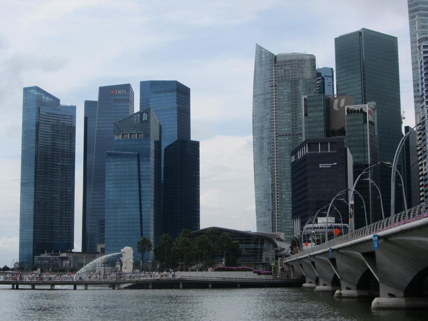 Skyline of the Singapore business district. The larger of two Merlions (half fish-half lion creatures) may be seen spouting along the pier. Singapore is one of the world's leading financial centers.