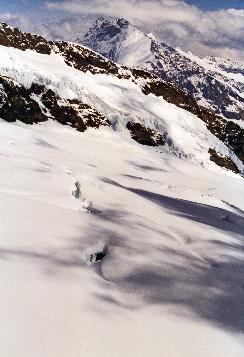 Snow, rocks, shadows, and peaks merge upward into the clouds. 