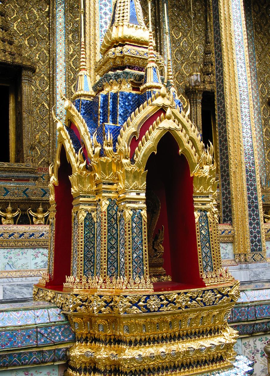 At the Grand Palace in Bangkok; the Palace complex features brightly colored buildings, golden spires, and glittering mosaics.  This close-up highlights the widespread and effective use of mirrored tiles in the construction process.