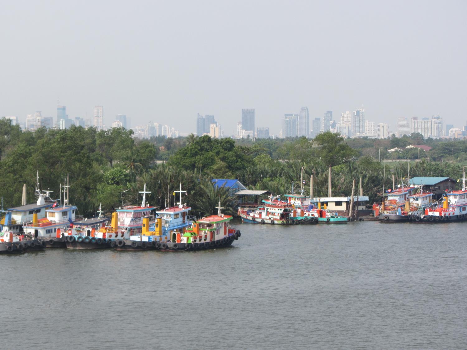 Fishing boats on the Chao Phraya River with the skyline of Bangkok in the background. 