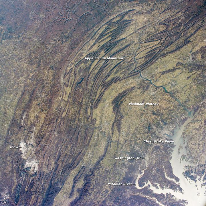This regional view shows the striking visual effect of the valley-and-ridge topography of the Appalachian Mountains as viewed from the International Space Station. The image shows more than 500 km (300 mi) of this low mountain chain from northeast Pennsylvania (top right) to southern West Virginia, where a dusting of snow covers a patch of land (lower left). 

Sunglint reflections reveal details of the Chesapeake Bay and the great bend of the Potomac River. Cities are difficult to detect from space during daylight hours, so the sickle-shaped bend of the river is a good visual guide for astronauts trying to photograph the nation's capital, Washington D.C. The farm-dominated Piedmont Plateau is the light-toned area between the mountains and the bay. 

The Appalachian Mountains appear striped because the ridges are forested, providing a dense and dark canopy cover, while the valleys are farmed with crops that generally appear as lighter-toned areas. (Farmland is even lighter than usual in this image because the fields are fallow after the harvest.) Photo courtesy of NASA.