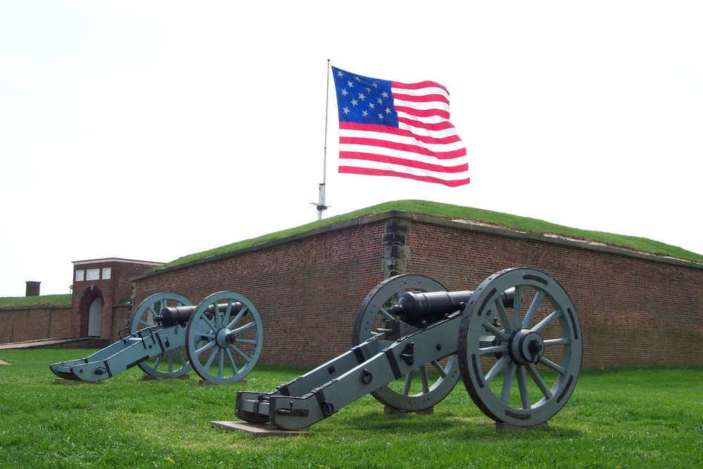 Two field pieces in front of Fort McHenry in Baltimore, Maryland with the garrison flag flying in the background. Photo courtesy of the National Park Service.
