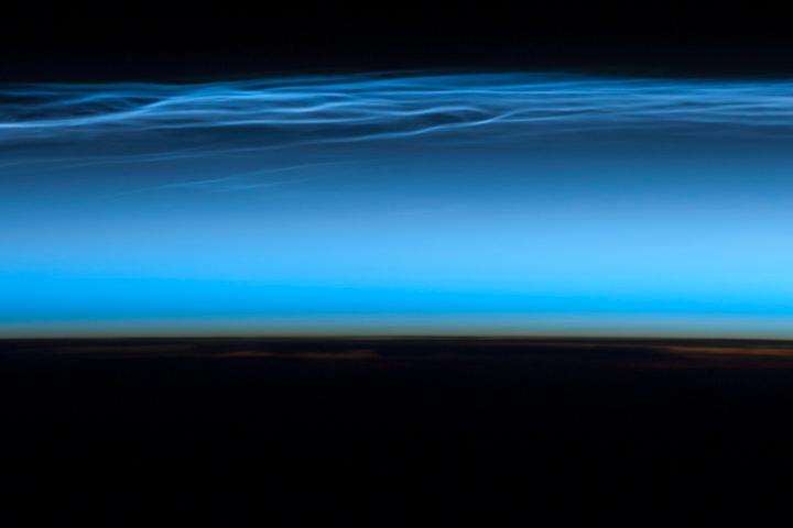 Polar mesospheric clouds - also known as noctilucent or "night shining" clouds - form between 76 to 85 km (47 to 53 mi) above the Earth's surface, near the boundary of the mesosphere and thermosphere, a region known as the mesopause. At these altitudes, water vapor can freeze into clouds of ice crystals. When the sun is below the horizon and the ground is in darkness, these high clouds may still be illuminated, lending them their ethereal, "night shining" qualities.

Polar mesospheric clouds have been observed from all human vantage points in both the Northern and Southern Hemispheres - from the surface, in aircraft, and from spacecraft - and tend to be most visible during the late spring and early summer. Image courtesy of NASA.