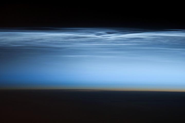 Polar mesospheric clouds - also known as noctilucent or "night shining" clouds - form between 76 to 85 km (47 to 53 mi) above the Earth's surface, near the boundary of the mesosphere and thermosphere, a region known as the mesopause. At these altitudes, water vapor can freeze into clouds of ice crystals. When the sun is below the horizon and the ground is in darkness, these high clouds may still be illuminated, lending them their ethereal, "night shining" qualities.

Polar mesospheric clouds have been observed from all human vantage points in both the Northern and Southern Hemispheres - from the surface, in aircraft, and from spacecraft - and tend to be most visible during the late spring and early summer. Image courtesy of NASA.