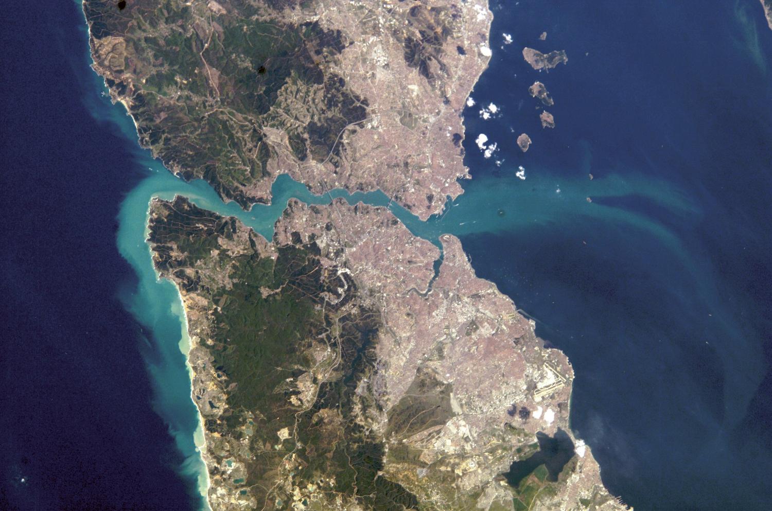 A view of Istanbul as taken from the International Space Station. The metropolis of 15 million occupies both sides of the entrance to the narrow, 32 km- (20 mi-) long Bosporus Strait connecting the Mediterranean and Sea of Marmara (south, on the right) to the Black Sea (north, on the left). When this image was taken, strong currents carried turbid coastal waters from the Black Sea through the Strait and into the Sea of Marmara. The sinuous waterway and harbor on the western shore are known as the Golden Horn. Image courtesy of NASA. 