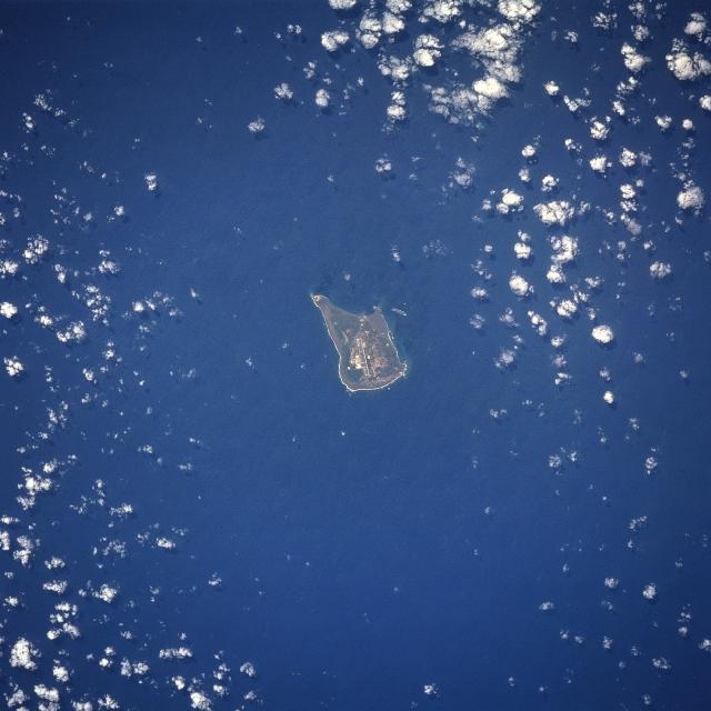 The largest of the three Volcano Islands, Iwo Jima is seen here from the north. The island is about 8 km (5 mi) long and 4 km (2.5 mi) wide, and covers an area of 21 sq km (8 sq mi). Mount Suribachi (167 m; 546 ft  high), on the south side of the island, is an extinct volcano. Iwo Jima was the scene of one of the bloodiest battles in the Pacific Theater of World War II. Image courtesy of NASA. 