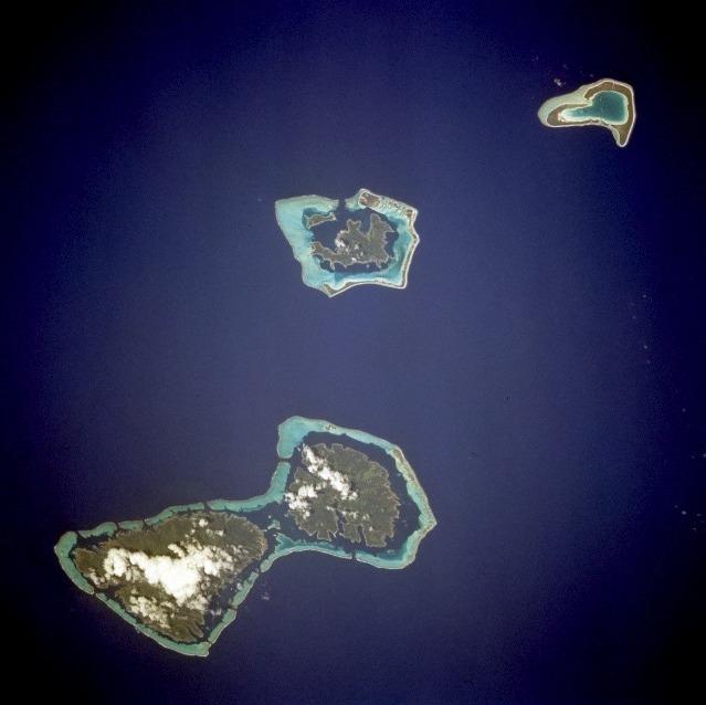Considered by many as one of the natural wonders of the world, the island of Bora-Bora is a single island surrounded by an extensive coral reef and a beautiful blue lagoon captured in the center of this low-oblique photograph. The coral reef north of Bora-Bora is Tupai Atoll. The two islands southeast of Bora-Bora - Tahaa (northern island) and Raiatea (larger southern island) - are encircled by a single coral reef system. Image courtesy of NASA. 