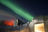 A full moon and 25 second exposure allowed sufficient light into this photo taken at Amundsen-Scott South Pole Station during the long Antarctic night. The station appears at the far left, the power plant in the center, and the mechanic's garage in the lower right. Red lights are used outside during the winter darkness as their spectrum does not pollute the sky, allowing scientists to conduct astrophysical studies without artificial light interference. The background of green light is the aurora australis, which dances through the sky virtually all the time during the long Antarctic night (winter). The photo's surreal appearance makes the station look like a futuristic Mars Station. Image courtesy of the National Science Foundation.