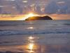 A sunset and its reflection create a golden sheen along a Costa Rican shoreline.