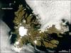 A rare break in the clouds allowed a satellite a chance to capture this photo-like image of the Kerguelen Islands. Located in the southern Indian Ocean roughly midway between Africa, Australia, and Antarctica, the Kerguelen Islands experience a fierce climate, with incessant, howling winds and rain or snow nearly every day. At a latitude of about 49 degrees south, the islands lie in the path of the "Furious Fifties," a belt of westerly winds that whip around the Southern Hemisphere, mostly unimpeded by land.

The islands were formed over millions of years by a series of lava flows. The perimeter of the large island is carved by fjords, and the rocky landscape is very sparsely vegetated with grasses, mosses, and a plant in the cabbage family. Glaciers are scattered across the island. The largest is Cook Glacier, in the west. The highest point on the island is Mount Ross, which has an elevation of 1,850 m; it is also thought to be the youngest volcanic peak on the island. In a handful of fjords, the water appears greenish. The color is probably due to very fine sediment ground down by the enormous friction the glaciers generate as they scrape over the land. Rivers and streams flush this sediment out to the coast.

Despite the challenging climate, several animals and birds make their homes at Kerguelen or use it as a stopping over point in their migrations or during breeding. Among the wildlife on the Kerguelen Islands are several species of penguins, elephant and fur seals, and dozens of species of birds, including terns and albatrosses. The sea makes this "wildlife sanctuary" possible; the islands are located along the Antarctic Convergence Zone, where the icy waters of the Southern Ocean meet the warmer waters of the Indian Ocean. The waters in this mixing area are very rich in nutrients, which support ocean plants (phytoplankton) that are the foundation of the ocean food web. Photo courtesy of NASA.