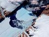 The Petermann Glacier grinds and slides toward the sea along the northwestern coast of Greenland, terminating in a giant floating ice tongue. Like other glaciers that end in the ocean, Petermann periodically calves icebergs. In July 2012, a massive ice island broke free and gradually drifted down the fjord, away from the floating ice tongue from which it calved. This satellite image has been rotated and north is toward the right. Analysis of the  image reveals that the iceberg covers an area of about 32.3 sq km (12.5 sq mi). Image courtesy of NASA.
