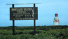 Sign on Howland Island proclaiming its status as a wildlife refuge. The "Earhart Light" day beacon (an unlighted nautical sea mark) is on the right. Photo courtesy USFWS/C. Newton