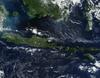 This true-color image of some of the Indonesian islands is from mid-May 2002. Fire season was not fully underway in the region, and skies over the large island of Borneo (top) were partially cloud-covered, but not hazy with air pollution. The horizontally situated island of Java appears to be experiencing some haze at its western end, and a few scattered fires (red dots) are apparent. Image courtesy of NASA.

