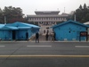 A face-to-face confrontation between South Korean and UN soldiers in the foreground and approaching North Korean guards.