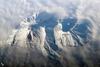 Russia's eastern Kamchatka Peninsula, which extends far into the Pacific Ocean, includes more than 150 volcanoes. While most are not actively erupting, many are considered dangerous due to their eruptive history and proximity to population centers and air travel corridors. This astronaut photo highlights the summit crater and snow-covered slopes of Avachinshy stratovolcano (2,741 m; 8,993 ft) as it pokes above a surrounding cloud deck. The volcano has an extensive historic and geological record of eruptions, the latest activity ocurring in 2008. To the southeast (image right), the large breached crater of Kozelsky volcano also appears above the clouds. Kozelsky is a parasitic cone, formed by the eruption of material from vents along the flank of Avachinsky. Photo courtesy of NASA.