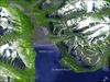Spitsbergen, the largest of the islands in the Svalbard Archipelago, sits well inside the Arctic Circle, just south of 80 degrees north latitude. This image of the island and its topography was captured by NASA's Terra satellite. The rugged mountains are capped with snow and glaciers, with only the river valleys and low elevations supporting vegetation. Braided, shallow rivers filled with glacial sediment occupy the valleys. The vertical scale is exaggerated by a factor of two to emphasize the rugged terrain. The small town of Longyearbyen serves as the capital; its small airport provides the most northerly public airline service on earth. Although coal mining is still an important economic activity on the frigid island, scientists have recently become as interested in what can be tucked away in the frozen mountains of Spitsbergen as what can be extracted from them. In late February 2008, Norway accepted the first deposit for a so-called "Doomsday" agricultural seed vault, drilled deep into the mountains overlooking the Svalbard Airport. Financed by Norway, the Svalbard Global Seed Vault will safeguard seeds of human food crops from all over the world in the event a natural or human-caused catastrophic event would threaten the human food supply. Photo courtesy of NASA.