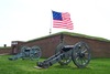 Two field pieces in front of Fort McHenry in Baltimore, Maryland with the garrison flag flying in the background. Photo courtesy of the National Park Service.