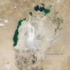 Throughout the first half of the 20th century, the Aral Sea was the world's fourth-largest lake. In the 1960s, the Soviet Union began a massive irrigation project in what are now Kazakhstan, Uzbekistan, and Turkmenistan, diverting water from the rivers that feed the Aral Sea to irrigate farmland. As its water levels dropped, the lake began splitting into smaller pieces: the Northern (Small) Aral Sea and the Southern (Large) Aral Sea. The Southern Aral Sea further split into eastern and western lobes. In August 2009 when this photo was taken, the Northern Aral Sea (upper right) still appeared healthy, the Southern Aral Sea consisted of two isolated water bodies: an irregular oval shape directly southwest of the Northern Aral Sea, and the long, thin remainder of the Southern Aral Sea's far western lobe. Much of what finally doomed the Southern Aral Sea was an attempt to save its neighbor to the north. In 2005, Kazakhstan built the Kok-Aral Dam between the lake's northern and southern portions to preserve water levels in the north. The Northern Aral Sea actually exceeded expectations with the speed of its recovery, but the dam ended prospects for a recovery of the Southern Aral Sea, which some authorities already regarded as beyond help. Lake sediments from this depleted water body have provided ample material for frequent dust storms. Image courtesy of NASA. 