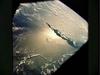 A sun glint in the southwestern Pacific Ocean, as photographed from an Apollo spacecraft. The island is Bougainville of the Solomon Islands group. The horizon of the Earth is in the background. The picture was taken at an altitude of 231 km (143 mi). Photo courtesy of NASA.
